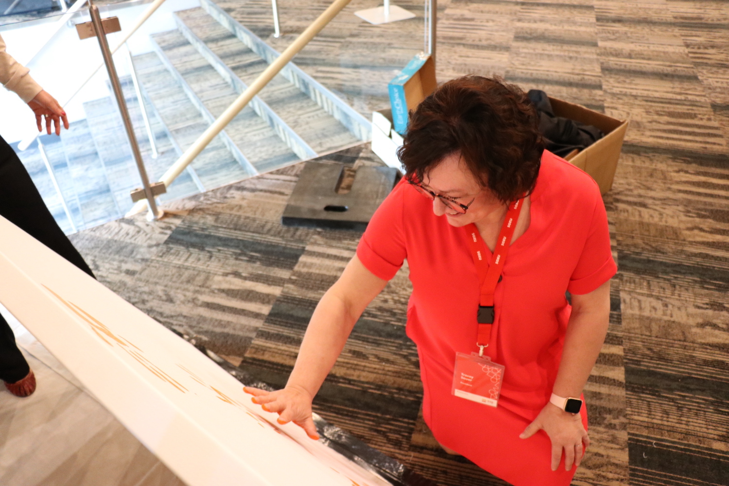 Tracey Sauer places an orange hand print on a canvas.